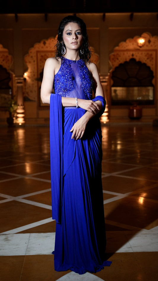 Woman in a blue saree standing in an ornate indoor setting