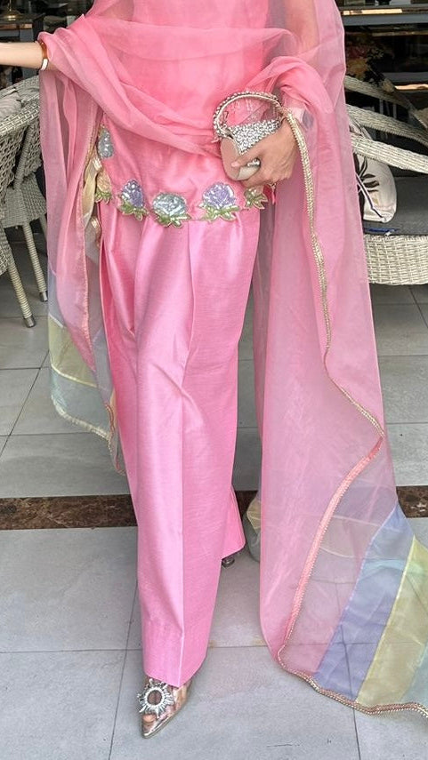 Person wearing a pink traditional outfit with a colorful dupatta in an indoor setting.