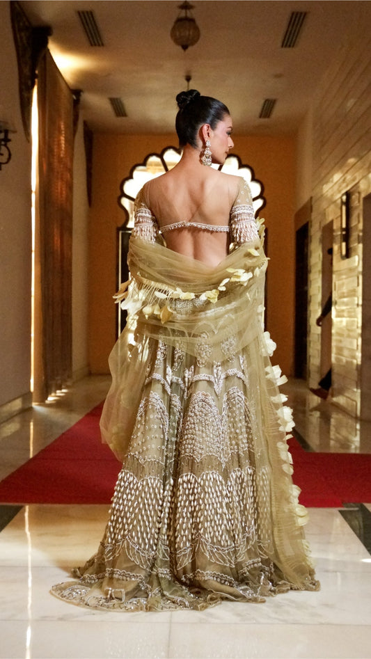 Woman in a traditional gold and white saree walking in a decorated hallway.