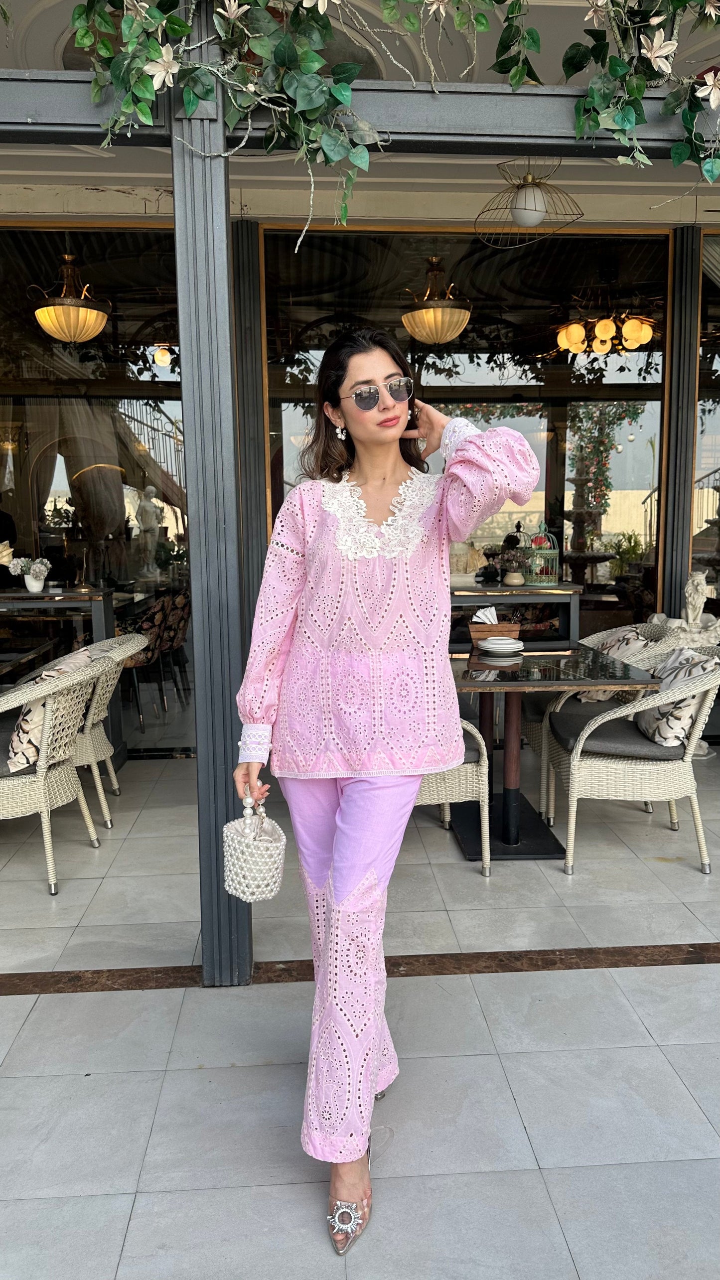 Woman in a pink outfit standing in an outdoor cafe setting