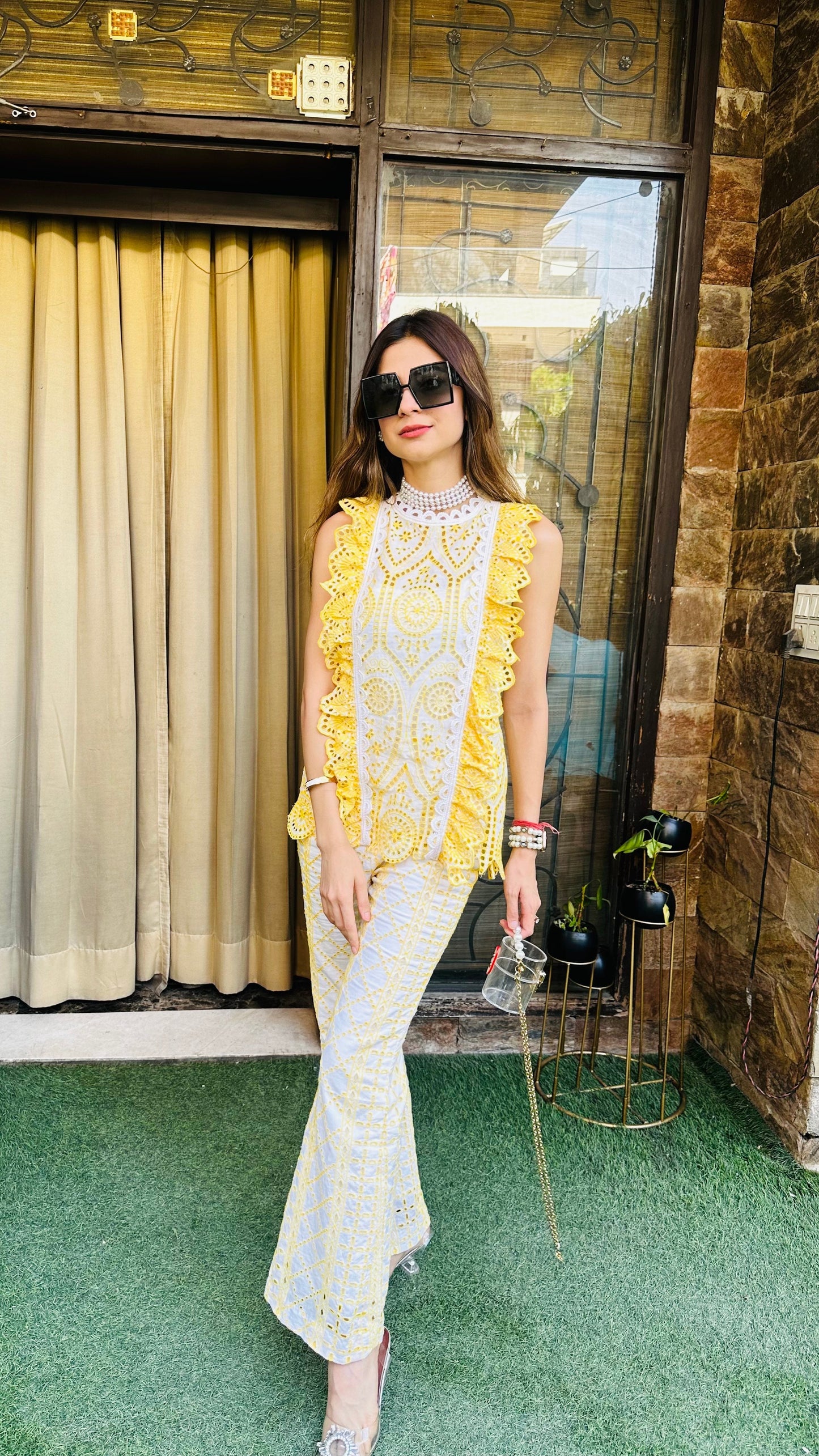 Woman in a yellow and white outfit standing in front of a building entrance.