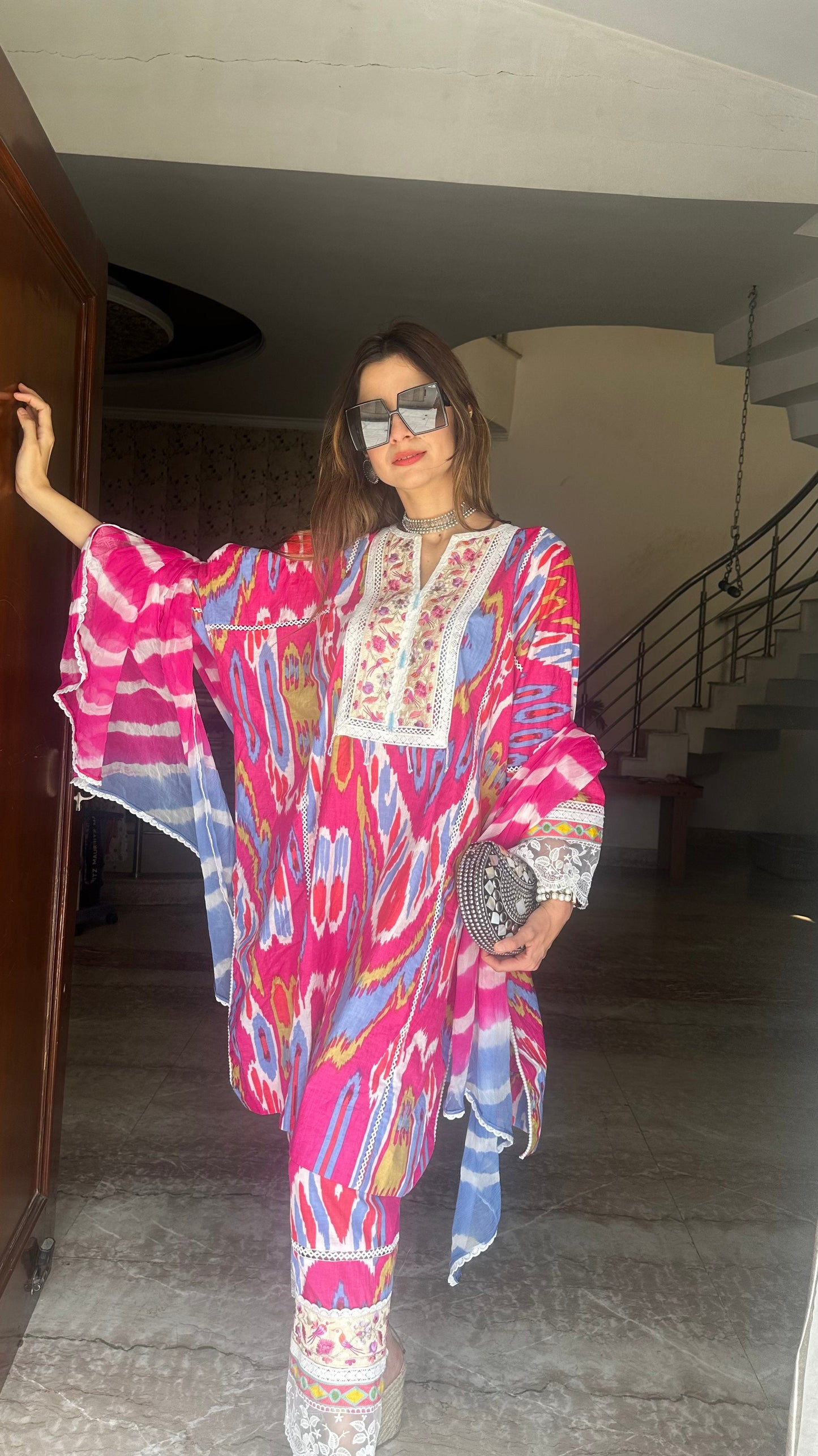 Woman in a colorful outfit standing indoors.