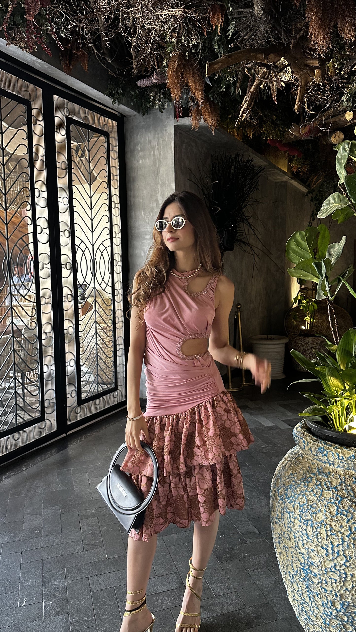 Woman in a pink dress standing in an indoor setting with decorative elements.