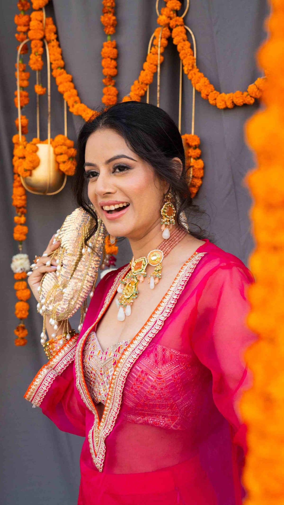 Woman in traditional pink saree with jewelry against a decorated background