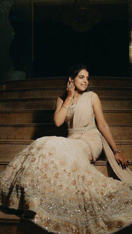 Woman in a formal gown sitting on a staircase in a dimly lit room.